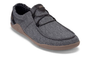 A single casual slip-on shoe with a gray fabric upper, black elastic laces, and a tan rubber sole designed for ultimate comfort. Perfect for digital nomads, it features branding on the tongue and heel, with stitching details around the edges.