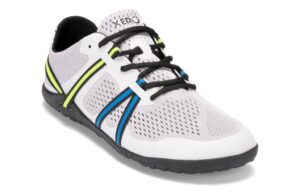 A white athletic shoe with a breathable mesh upper offers comfort for digital nomads, featuring black laces and blue and yellow stripe accents. The shoe has a black sole, a white toe cap, and the brand name on the tongue.