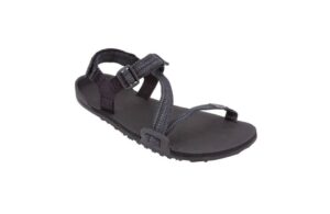 A black outdoor sandal with adjustable straps and a textured sole designed for comfort. Featuring a loop for the big toe and a plastic buckle, this lightweight footwear is perfect for digital nomads seeking casual or hiking adventures.