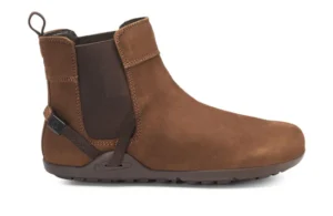 A brown ankle-high leather Chelsea Boot from Xero Shoes with a pull tab at the back, elastic side panel, and dark rubber sole. This stylish design also features a small strap detail near the heel for modern flair.