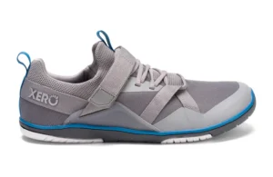A grey athletic shoe with mesh fabric, light grey overlay accents, a Velcro strap, blue trim, and a white sole. The Forza Trainer by Xero Shoes features blue pull tabs and the brand name on the heel—perfect for performance footwear enthusiasts.
