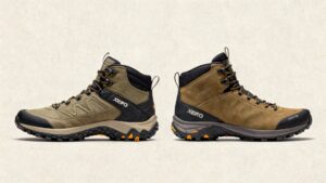 Two tan Xero Shoes Scrambler Mid hiking boots with black soles and orange accents are displayed side by side facing left. Both boots have 'XERO' branding on the side and visible laces, shown against a light beige background.
