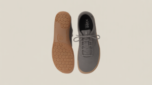 A pair of gray barefoot shoes is shown from above, with the left shoe displaying the tan rubber sole and the right shoe showing the top view. The sole has a hexagonal tread pattern—great for those seeking transition tips.