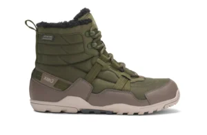 An olive green and brown Xero Winter Boot with lace-up front, textured sole, reinforced toe, and black fleece lining. The boot has "Xero" branding on the side, a loop on the heel, and is ready for Alpine adventures in Denver.