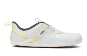 A white athletic slip-on shoe with yellow accents, gray inner lining, mesh upper, and the brand name "Xero Shoes" on the side. It features a pull tab at the heel and a flat sole for easy wear and comfort.
