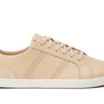 A beige low-top sneaker from Xero Shoes with a white sole, beige laces, suede detailing at the heel, and perforated side stripes. The shoe is photographed from the side on a white background.