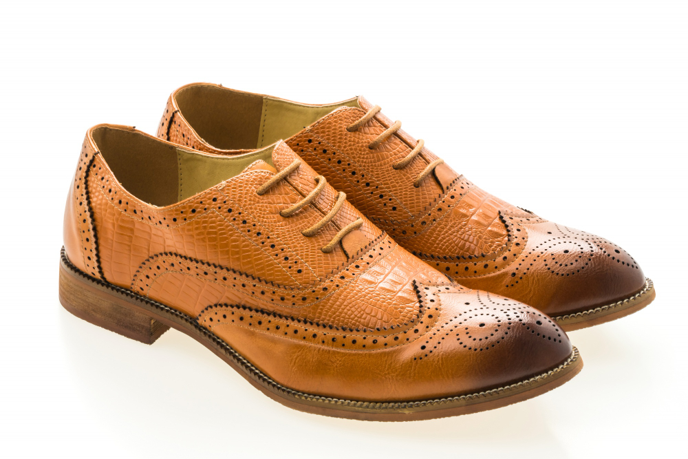 Pair of brown leather barefoot brogue shoes on a white background.